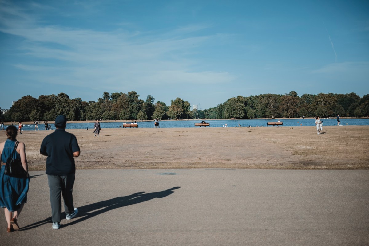 Een koppel loopt naar een meer in Hyde Park, Londen, op een mooie zomeravond.