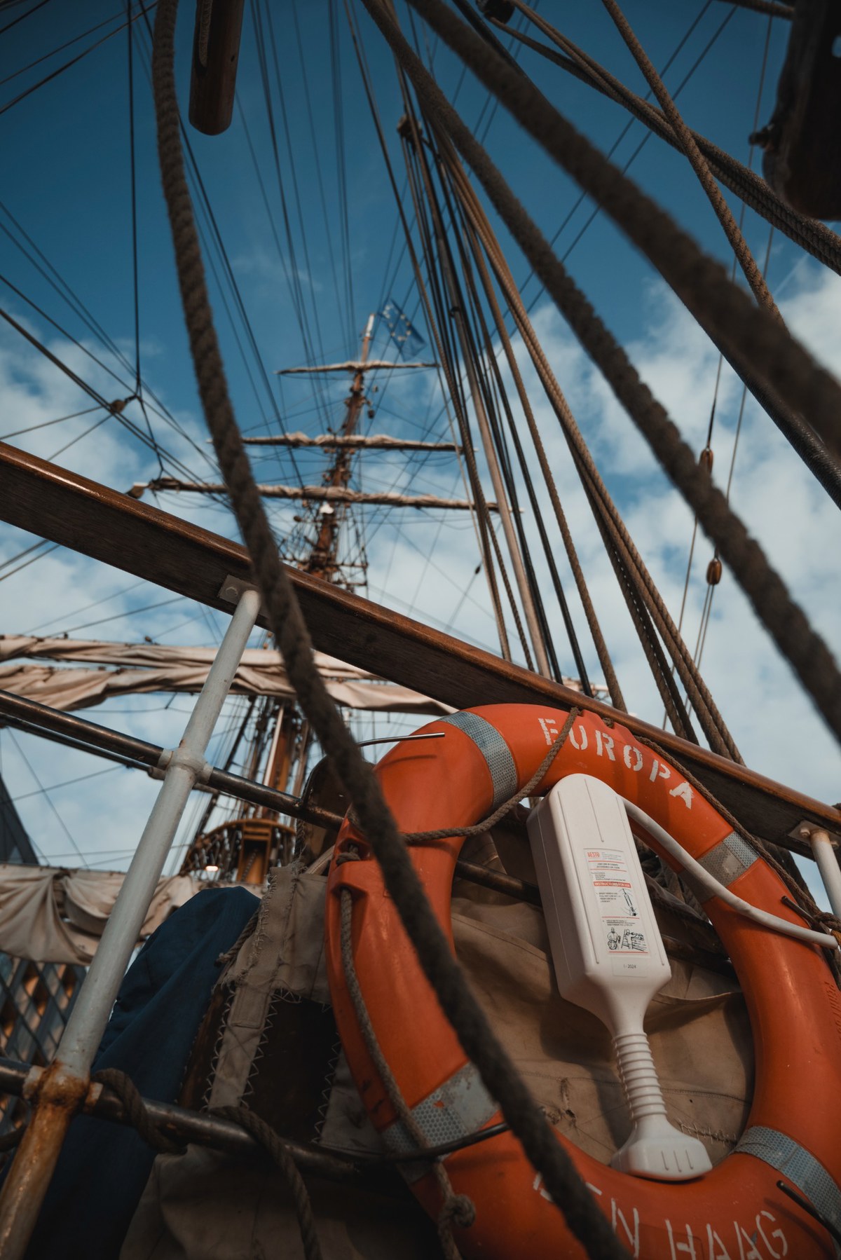 Een reddingsboei met 'Europa' op de voorgrond, de mast van de Bark Europa op de achtergrond