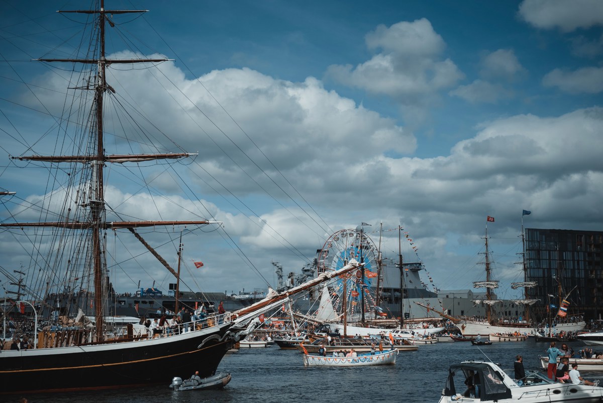 Een groot schip tijdens SAIL Amsterdam, met de Bark Europa aan de overkant