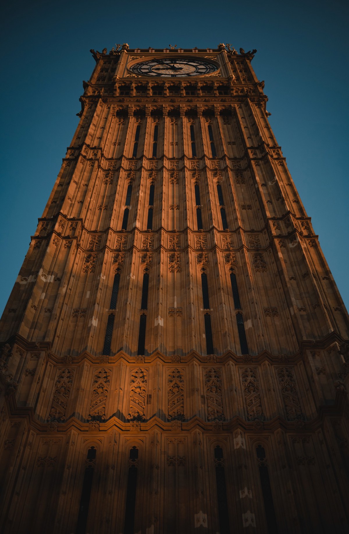 De Big Ben in Londen, van onderaf met het zonlicht erop, op een zomeravond.