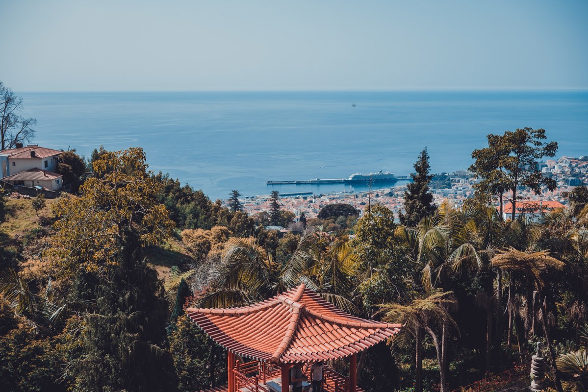 Een gebouw in Aziatische stijl en daarachter het park, nog verder Funchal en daarachter de zee
