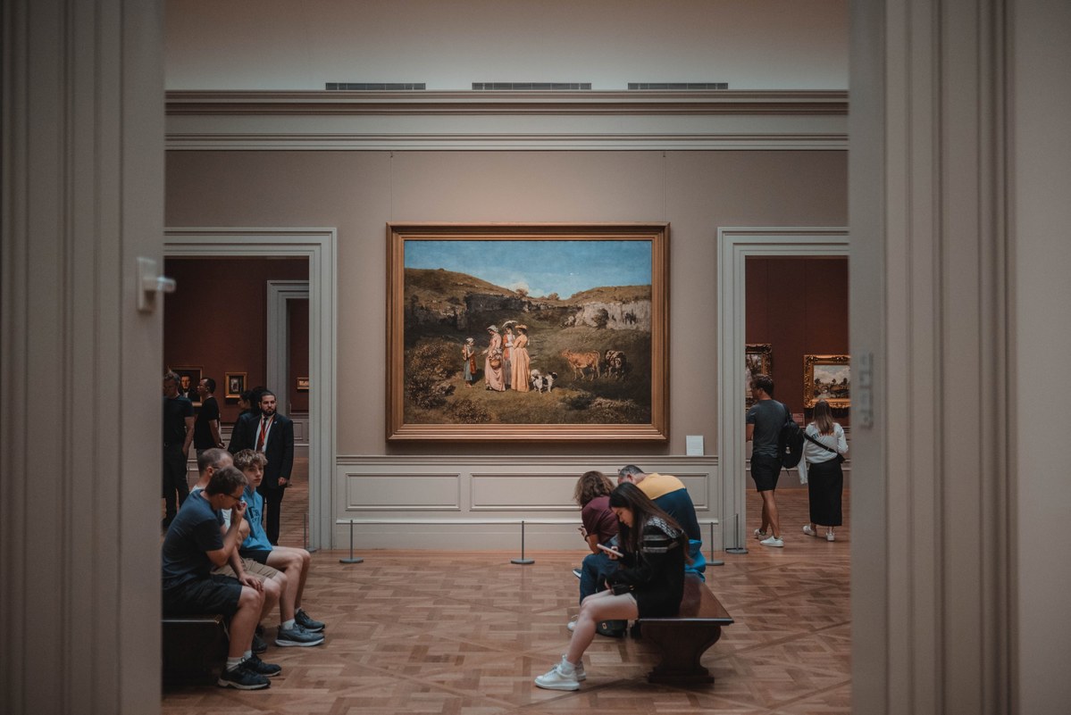 Een schilderij hangt in een hal met bezoekers