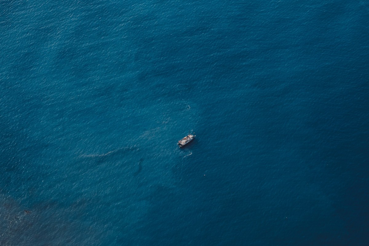 Een enkele boot in het midden van de blauwe zee