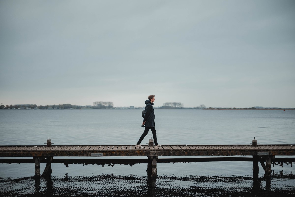Tim loopt over een vlonder, achter hem het meer bij Veere