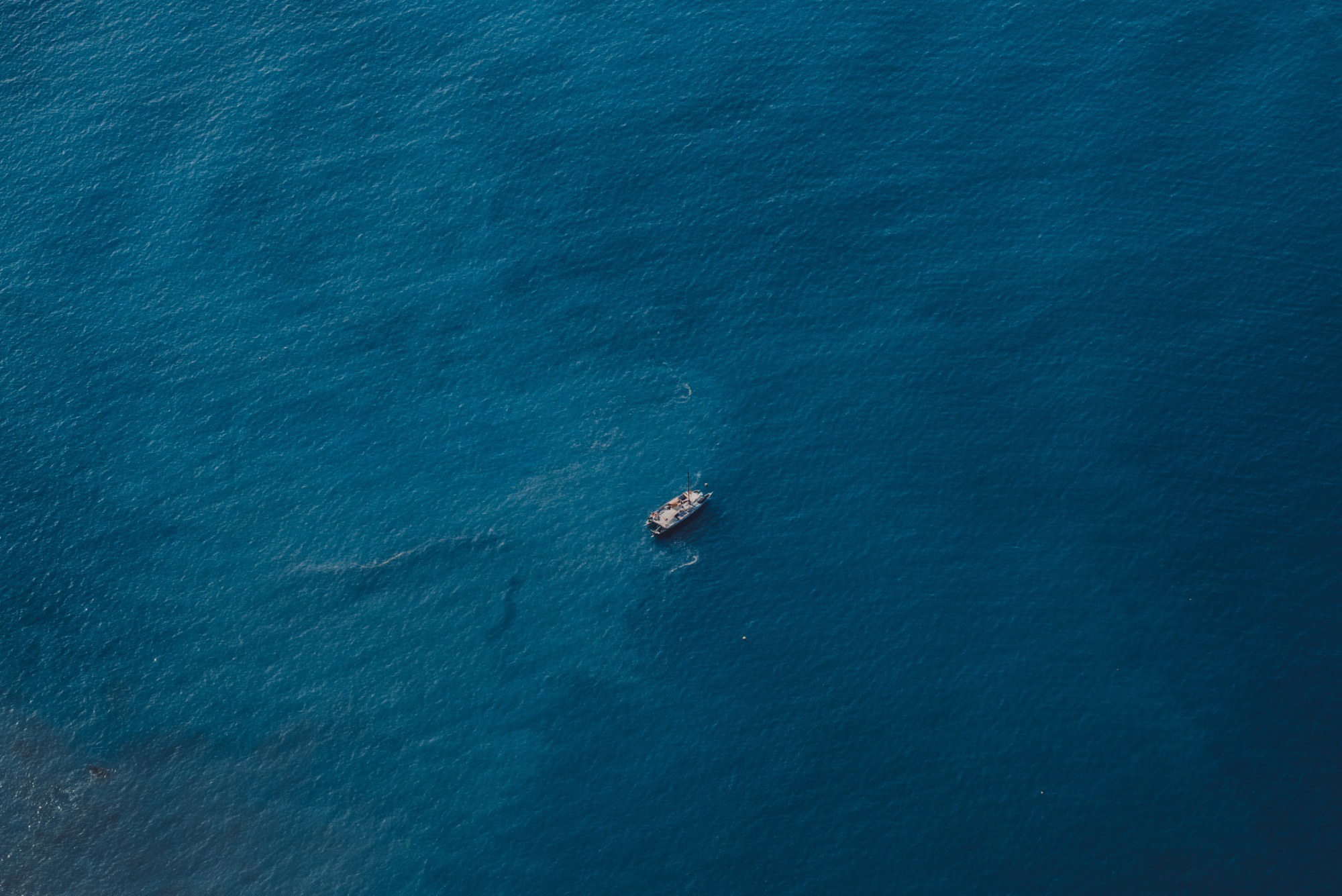 Een enkele boot in het midden van de blauwe zee