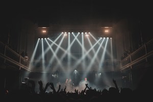Een foto van achterin de zaal van Paradiso. De spots richten van bovenin de zaal op het podium.