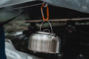 Een kleine ketel hangt aan een Thule Approach daktent