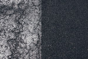 Verweerde witte wegmarkering vervaagt op donker asfalt, waar de afgesleten verf overgaat in het onbeschilderde, korrelige wegdek.