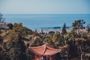 Een gebouw in Aziatische stijl en daarachter het park, nog verder Funchal en daarachter de zee