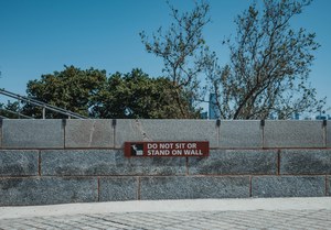 Een bordje 'Do not stand on wall' bij het vrijheidsbeeld.
