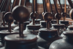 Rijen antieke wetenschappelijke instrumenten met glanzende houten bolknoppen op metalen stangen, warm belicht in het Teylers Museum.