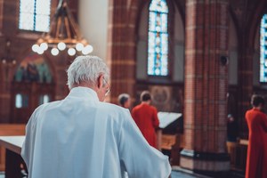 Herman Finkers draagt voor in de kerk. We zien Wishful Singing op de achtergrond.
