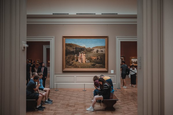 Een schilderij hangt in een hal met bezoekers