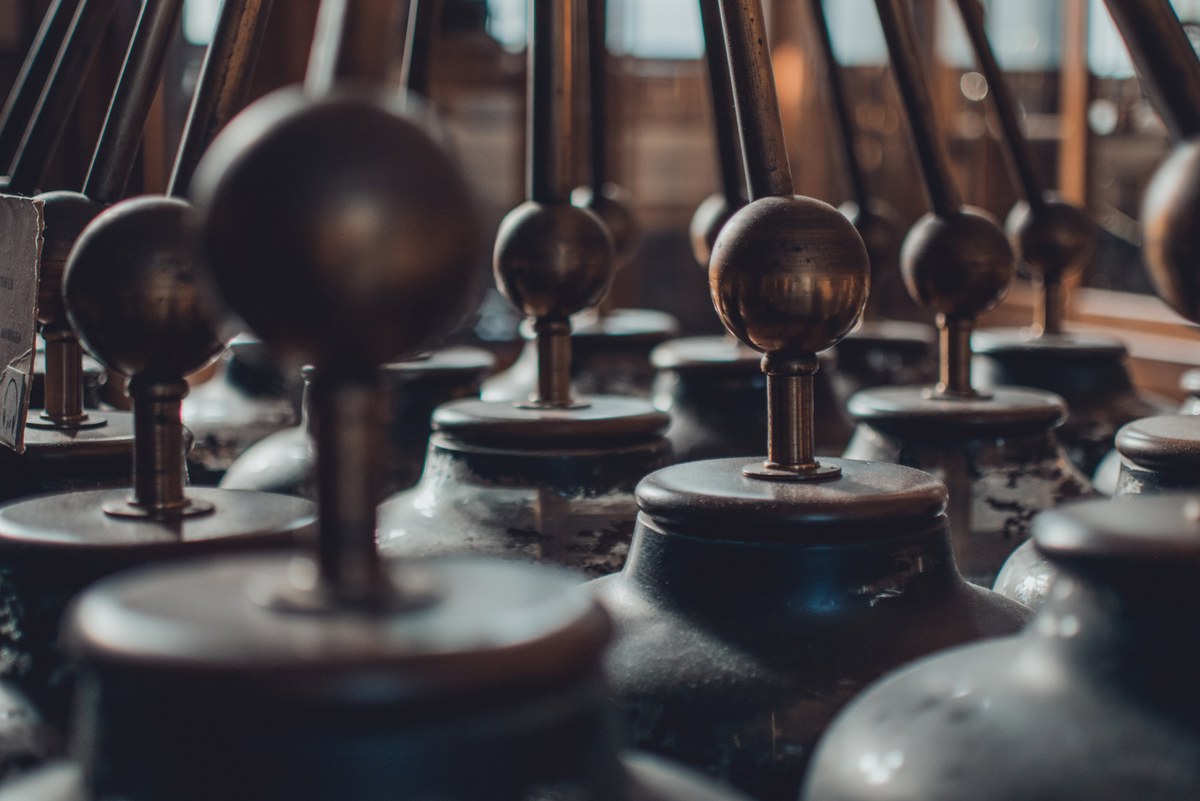 Rijen antieke wetenschappelijke instrumenten met glanzende houten bolknoppen op metalen stangen, warm belicht in het Teylers Museum.