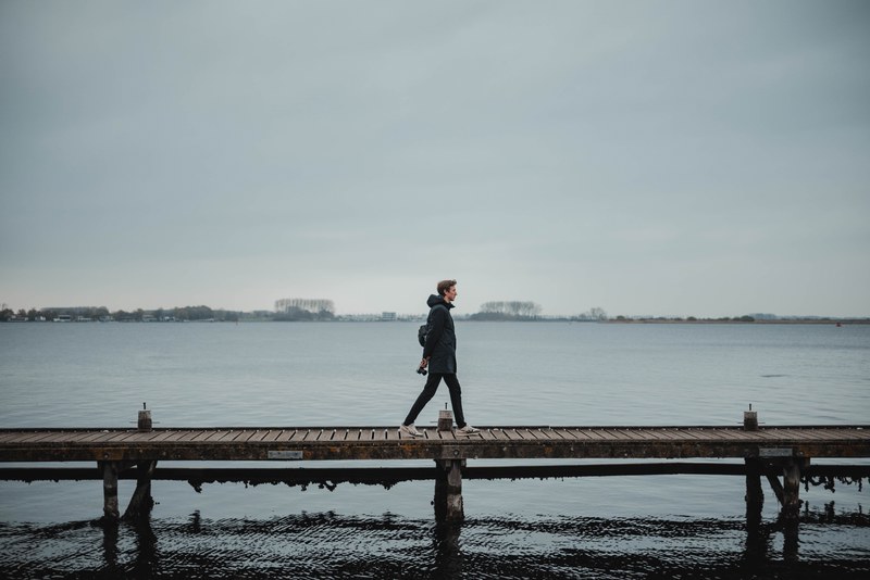 Tim loopt over een vlonder, achter hem het meer bij Veere