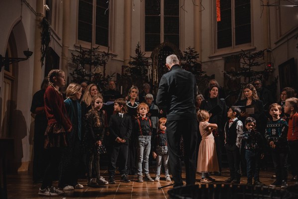 Dirigent met zangers en kinderen
