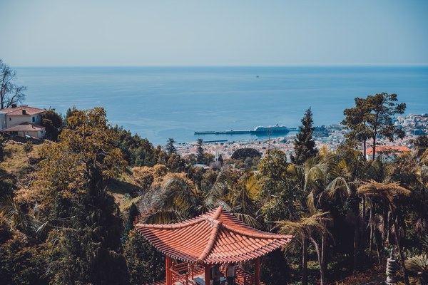 Een gebouw in Aziatische stijl en daarachter het park, nog verder Funchal en daarachter de zee
