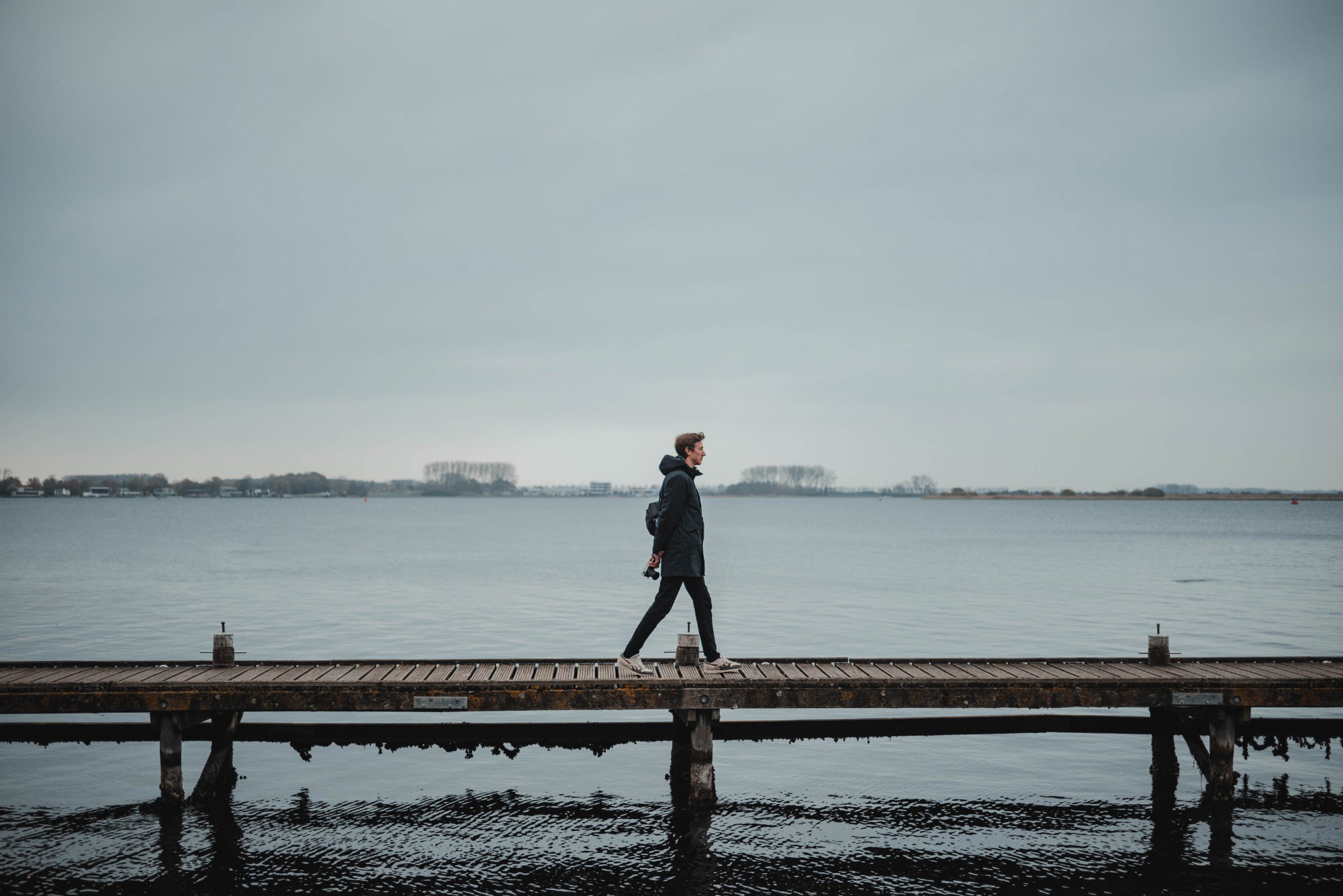 Tim loopt over een vlonder, achter hem het meer bij Veere