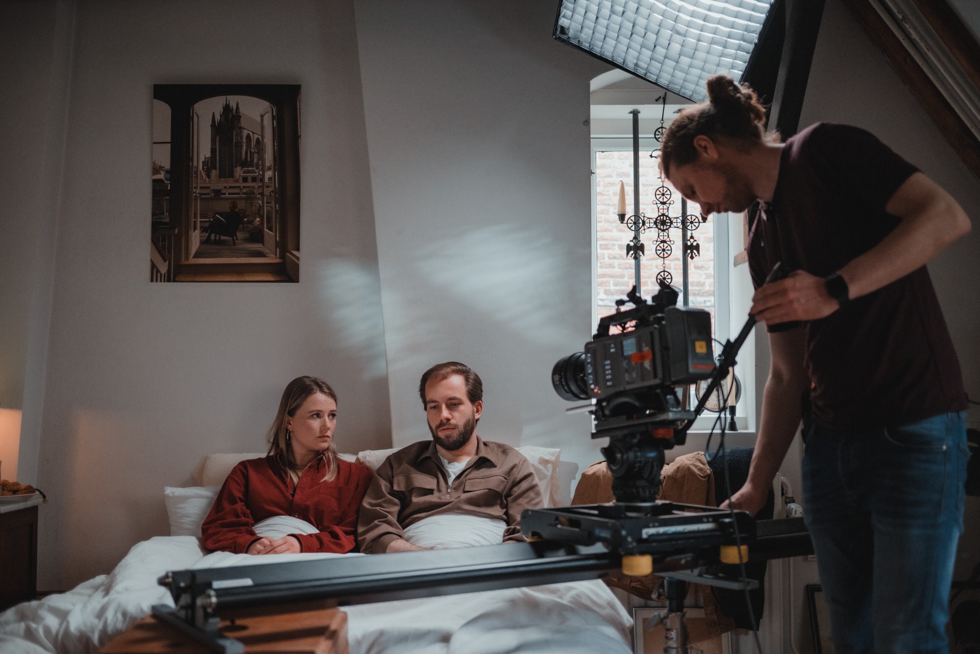 Twee acteurs in bed bij De Verdwenen Nacht, terwijl de cameraman scherp stelt.